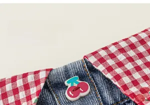 Détail de la jupe pour fille en vichy rouge et denim avec un bouton décoratif cerise