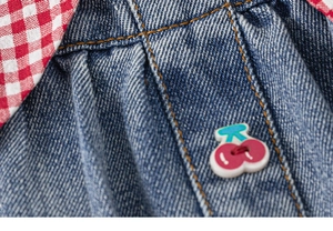 Détail d'une jupe en jean pour fille montrant un bouton cerise et doublure vichy