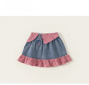 Détail d'une jupe en jean pour fille avec des volants vichy rouges et boutons cerise