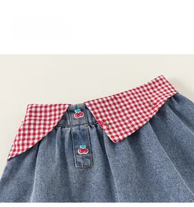 Détail du col en jean avec bordure à carreaux rouges et boutons en forme de cerise