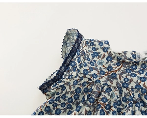 Dettaglio del vestito floreale per bambina con pizzo a sfera e trama del tessuto blu