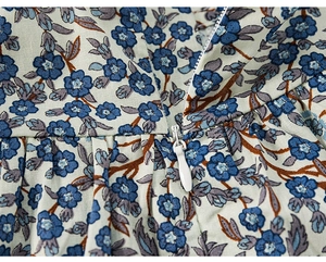 Dettaglio della cerniera bianca e della stampa floreale blu sul vestito estivo da bambina