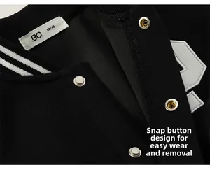 Detail shot of a black baseball jacket featuring silver snap buttons and a striped collar