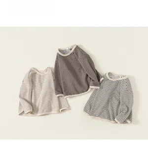 Close-up of three long-sleeved striped cotton t-shirts in beige, brown, and black-white