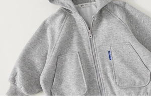 Detail of gray hooded sweatshirt showing zipper, fabric texture, and side brand tag
