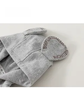 Detail of grey hooded jacket featuring 3D ears with embroidered letters and soft knit texture