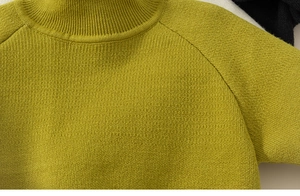 Detail van een grasgroene gebreide trui met opstaande kraag en raglanmouwen voor kinderen
