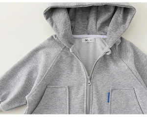 Close-up of gray hooded jacket featuring premium knit texture and secure resin zipper