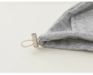Detailed macro view of the silver metal drawstring toggle on gray knitted fabric