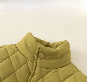 Close-up of olive green quilted jacket collar with round snap button and diamond patterns