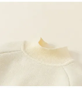 Detailopname van de geribbelde opstaande kraag en gebreide textuur op de witte trui