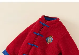 Détail d'une veste en polaire rouge pour enfant avec boutons et broderie dragon