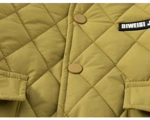 Close-up of mustard yellow quilted fabric with diamond patterns and matte snap buttons