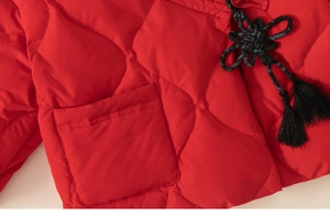 Detail der roten Steppjacke mit traditionellen chinesischen Knoten und schwarzen Quasten