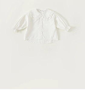 Close-up of the large lace-trimmed collar and ruffle details on this girls white shirt