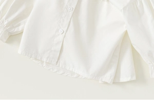 Detail view of cotton white long sleeve girl shirt featuring fine texture and wrist ruffles