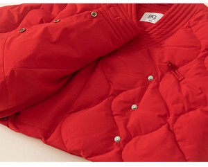Detail der roten gesteppten Daunenjacke mit Metalldruckknöpfen und gewebtem Markenetikett