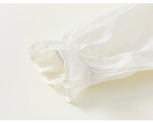Detailed close-up of white cotton girl shirt sleeve with elastic ruffled cuff design