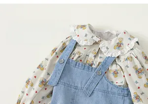Detail von Mädchenbluse mit Spitzenkragen und Kleid mit Cartoon-Bären-Aufdruck