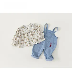 Flachbild-Detail von geblümtem Mädchen-Hemd und Jeans-Latzhose mit Herz-Stickerei
