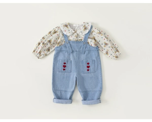 Detail von Baby-Mädchen-Blumenhemd mit Spitzenkragen und Denim-Latzhose mit Herzstickerei