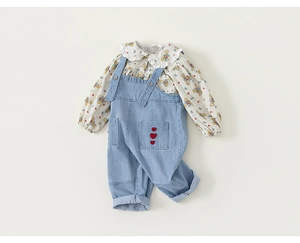 Detail der langärmeligen Blumenbluse mit Bärendruck und Denim-Latzhose mit Herz-Stickerei