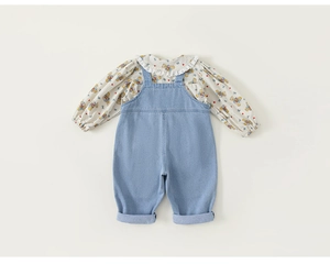 Detailaufnahme von Blumenhemd mit Rüschen und hellblauer Denim-Latzhose für kleine Mädchen