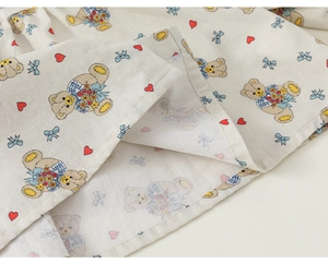 Detailaufnahme von cremefarbenem Baumwollstoff mit Bärenmuster und sauberem Saumstich