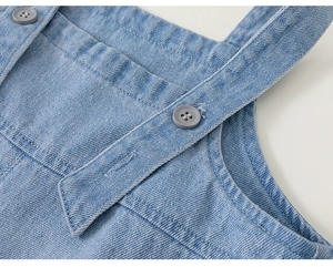 Detailansicht der Jeans-Latzhosen-Schultergurte mit grauen Knöpfen und feinen Nähten