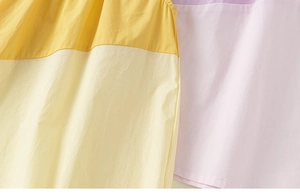 Detail of color-block cotton fabric showing yellow, purple and pink panel textures