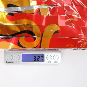 Close-up of red and gold foil fringe curtain backdrop weighing 32.7g on a digital scale