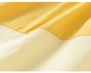 Detail of soft yellow and off-white color-block fabric with smooth texture and clean stitching