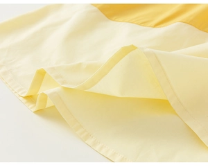 Detail shot of the contrast color hem with neat stitching on girls cotton A-line dress