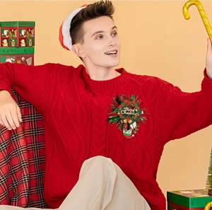 Nahaufnahme einer Weihnachtskranz-Anstecknadel mit roter Schleife auf einem roten Pullover