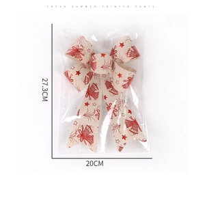 Detailed view of red Christmas bow with bell prints in packaging, size 27.3 x 20 cm