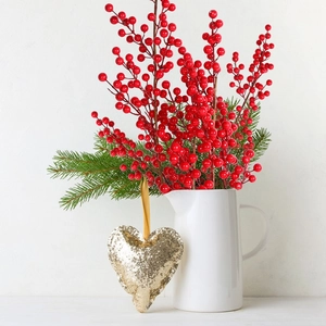 Detail of red artificial berries with pine needles in a ceramic vase for Christmas decor