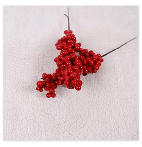 Macro detail of glossy red artificial berries on brown stems over white plush background