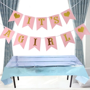 Detail of pink It's a Girl banner and shiny light blue foil tablecloth for party decor