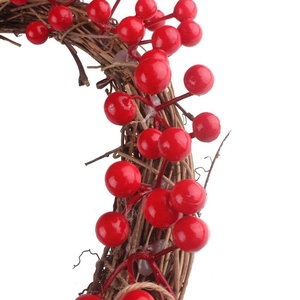 Gros plan détaillé de baies rouges tissées dans une base de couronne de Noël en vigne