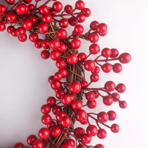 Gros plan d'une couronne de baies rouges avec base de vigne naturelle pour Noël