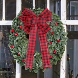 Christmas wreath with green needles, red berries, LED lights and red plaid bow decoration