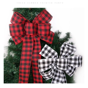 Close-up of buffalo plaid Christmas bow ornaments hanging on festive green tree branches