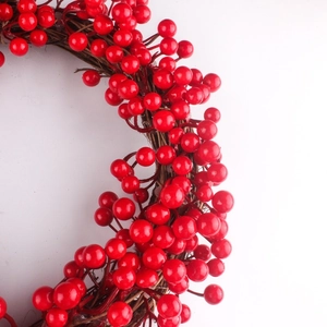 Gros plan d'une couronne de Noël en baies rouges avec une texture de vigne en rotin marron