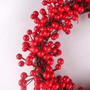 Gros plan d'une couronne de Noël aux baies rouges avec détails de la base en vigne brune