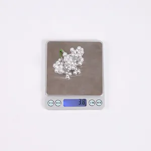 Close-up of lightweight silver foam berry ornament weighing 3.8g on a digital scale