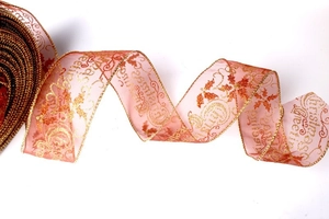 Close-up of pink sheer organza Christmas ribbon with gold leaf print and greetings