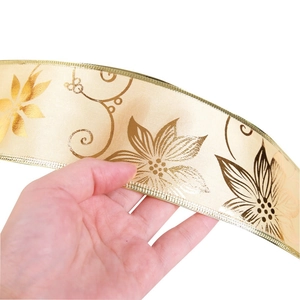 Detail of Christmas ribbon with gold poinsettia print and metallic edge finish