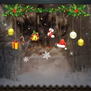Detail of Christmas window clings featuring green pine branches, red berries, and gold bells