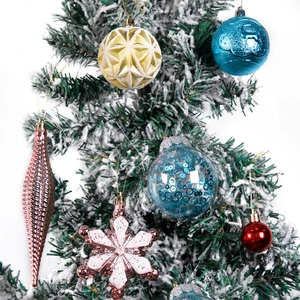 Assorted Christmas ornaments including glitter spheres and deer motifs on snowy tree branch