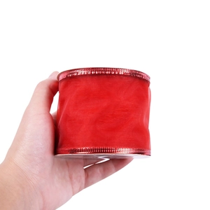 Detail of red mesh Christmas ribbon with metallic edges held in hand for crafts